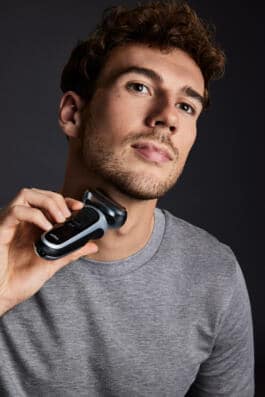 Footballer Goretzka using electric razor on neck 