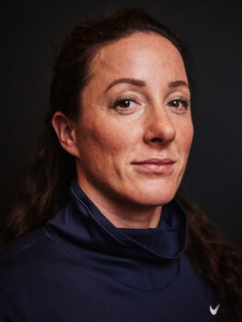Tatyana McFaddon for Nike, Paralympics wearing a navy collared shirt, looking slightly to the side, set against a dark background. 