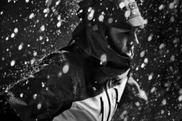 Hedvig Wessel Free ski World Chamption in a raincoat navigates through heavy rain, with water droplets dramatically captured in motion, creating a dynamic, monochrome scene. 