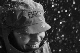 A smiling Hedvig Wessel Free ski World Chamption in rain gear adorned with droplets, enjoying a rainy moment. 